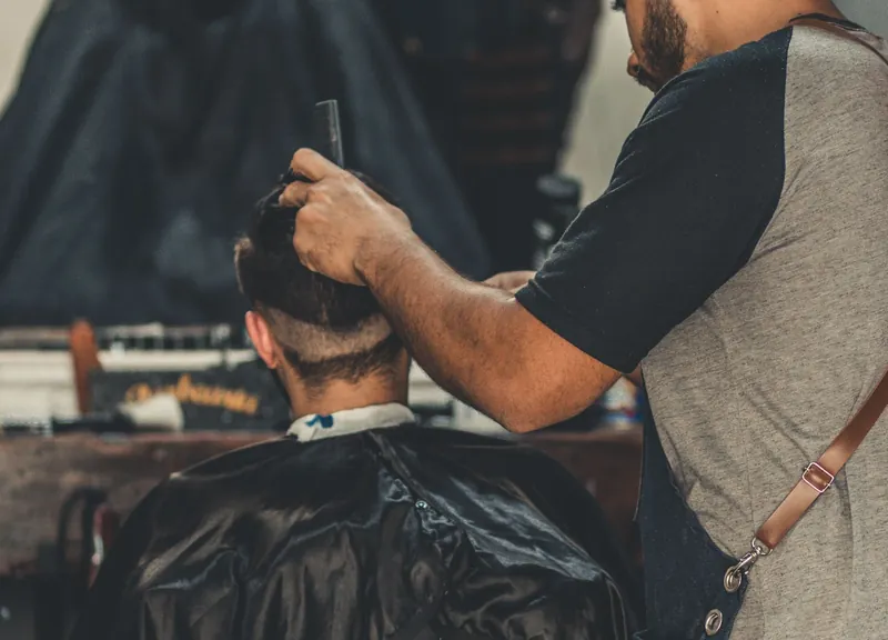 Barbeiro atende cliente em barbearia de São Paulo