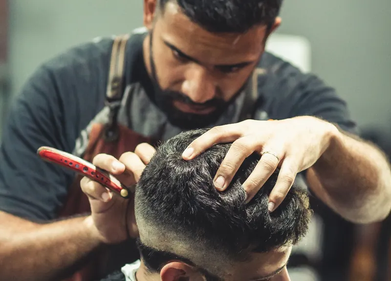 Barbeiro atende cliente em negócio de São Paulo